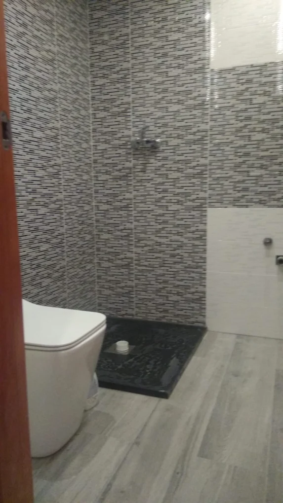 Reforma de baño con ducha gresite, plato negro y suelo imitación madera Madrid